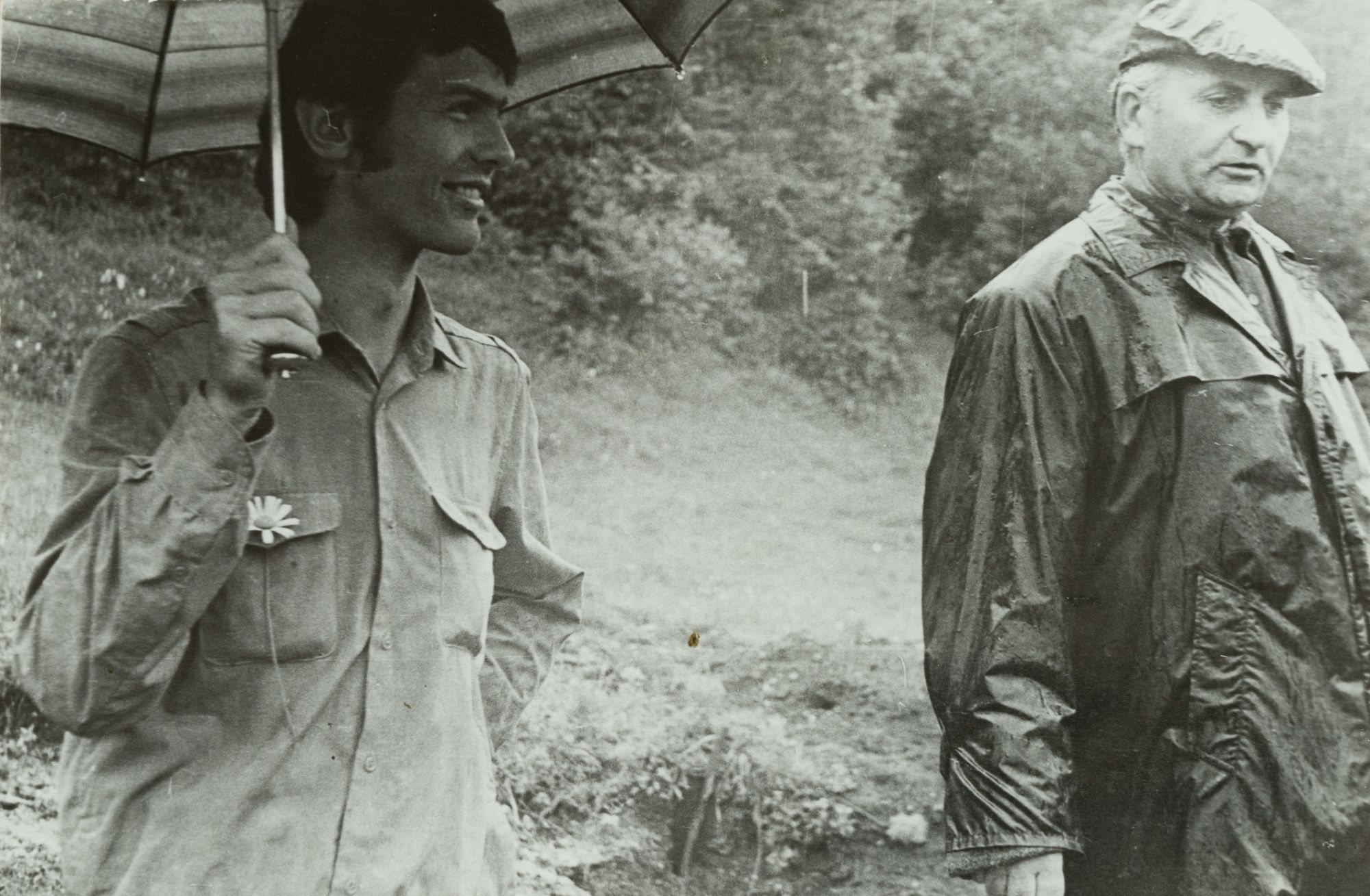 Volodymyr Ovsiichuk and a Man Under an Umbrella Against the Landscape